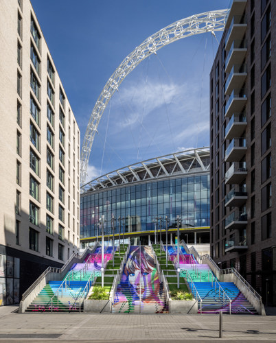 A bright, colourful mural depicting Taylor Swift's face adorns a triple stairway leading to the Wembley Arena